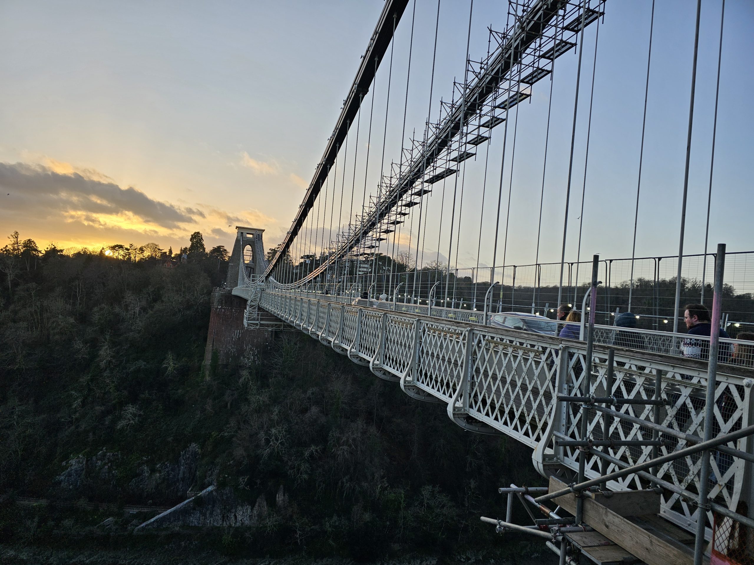 A view of the Clifton Suspension Bridge from one end, showcasing its architectural design and the surrounding landscape