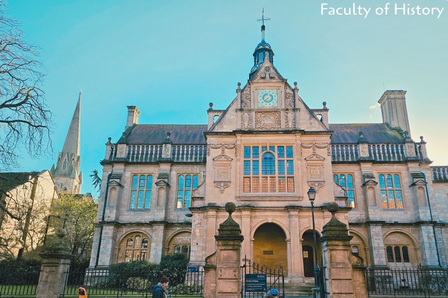 Faculty of History building at Oxford University, featuring honey-hued stone and striking blue-tinted windows, exuding a majestic and academic atmosphere.