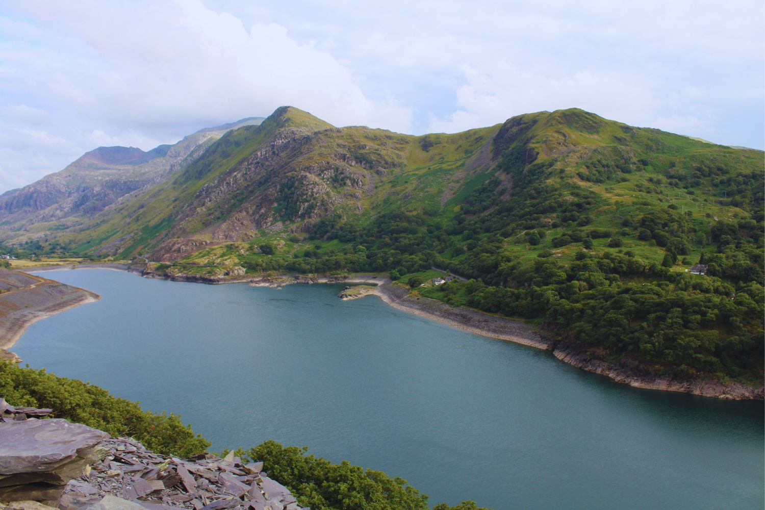 A stunning view of Llyn Peris and its surroundings from the top of Dinorwig Slate Quarry, showcasing the deep blue lake nestled between rugged slate hills and the dramatic landscape of Snowdonia.