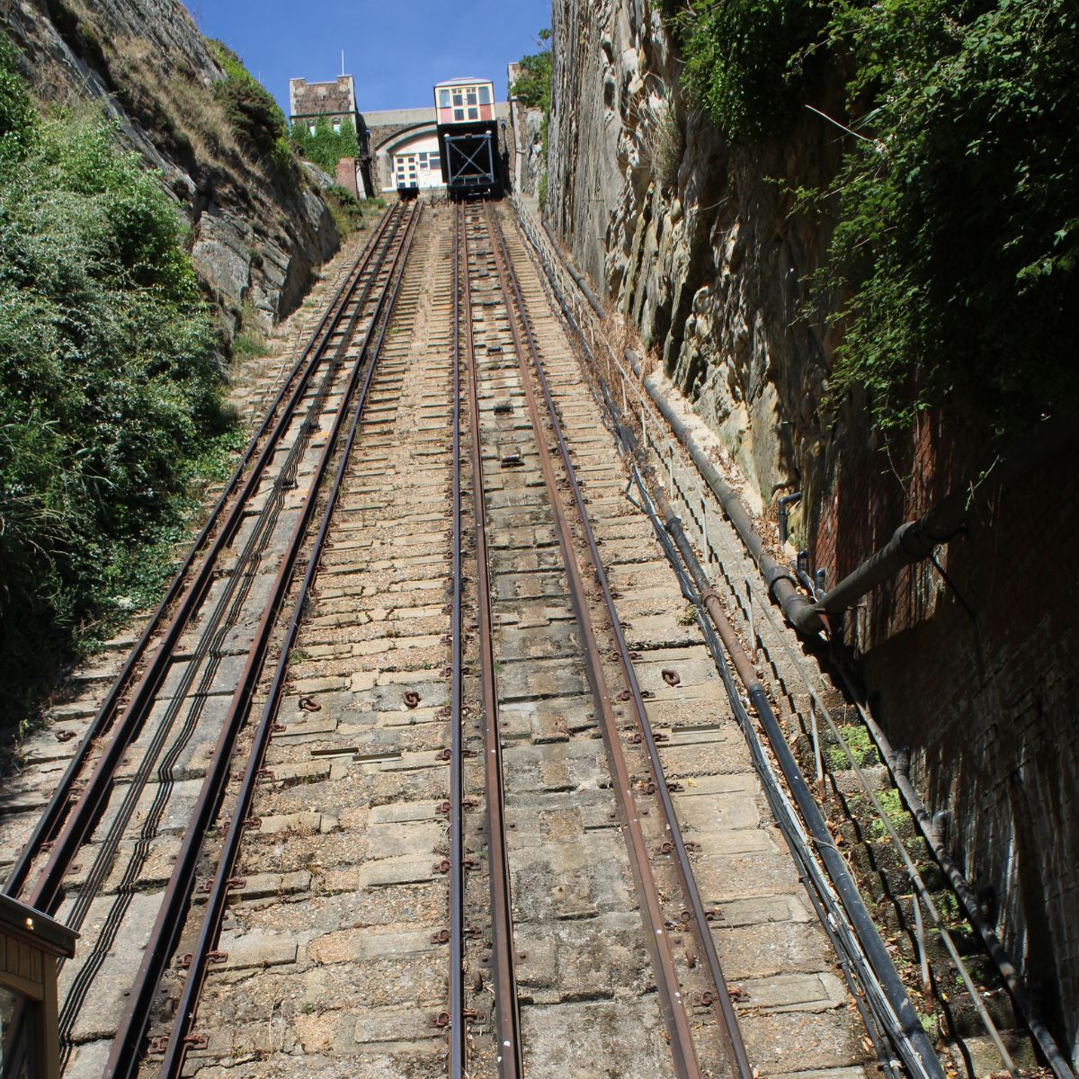 Historic funicular railway climbing the East Hill in Hastings with views of the coastline and town below on a clear day.