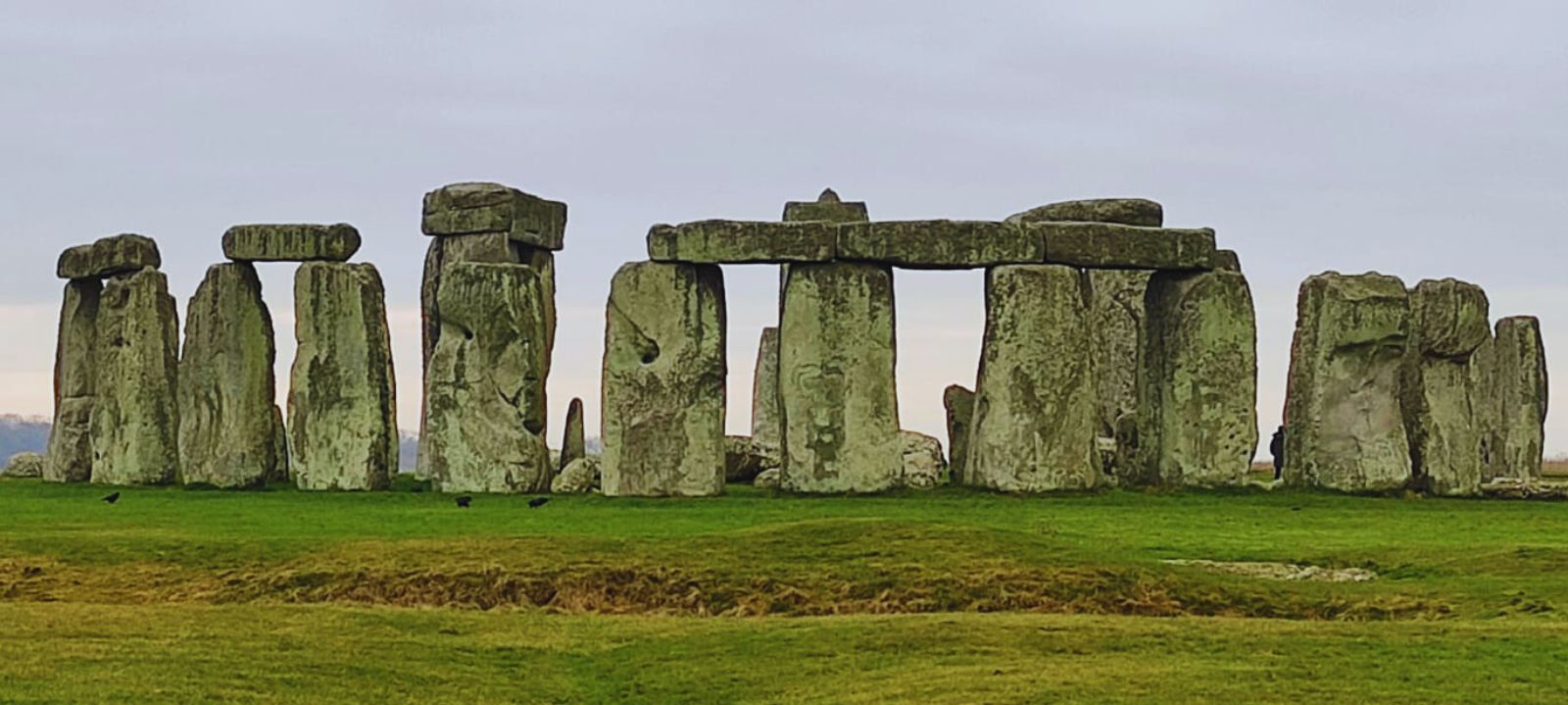 Stonehenge stone circle surrounded by green fields under a cloudy sky, a historic landmark near Salisbury.